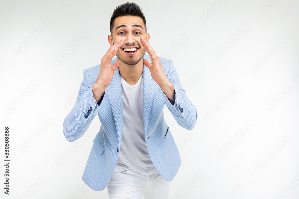 young guy in a blue jacket screams while holding hands near his mouth on a white background with copy space young guy in a blue jacket screams while holding hands near his mouth on a white background with copy space