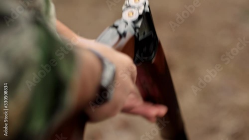 A man loads a barrel shotgun outdoors