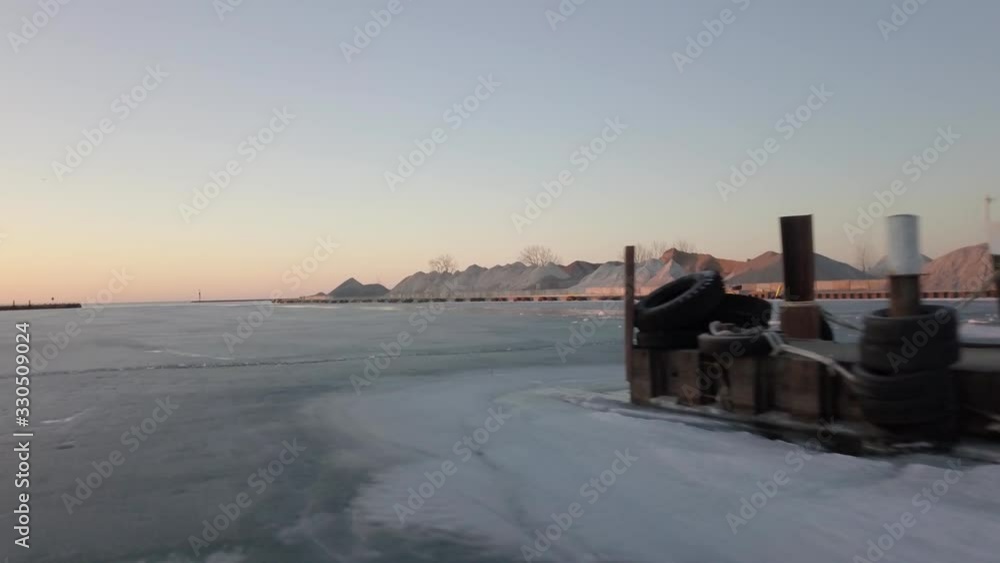 Low aerial over icy lake marina, one ship at the pier, gravel piles Low aerial over icy lake marina, one ship at the pier, gravel piles