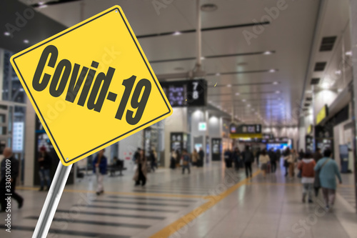 Crowd of people at airport with Covid-19 Sign
