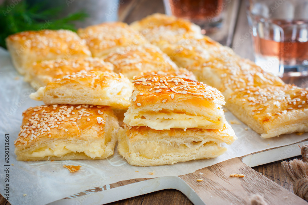 Puff pastry pie with cheese, sprinkled with sesame seeds, selective focus Puff pastry pie with cheese, sprinkled with sesame seeds, selective focus