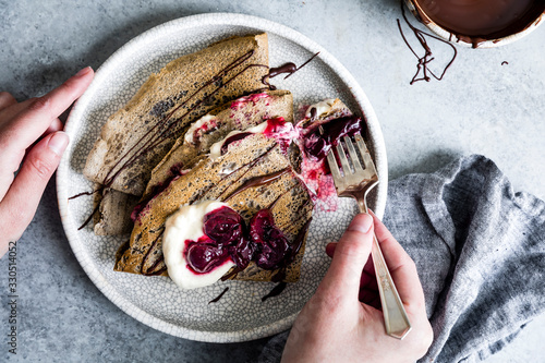 Toasty and nutty buckwheat crepes topped with roasted cherries, whipped cream, and bittersweet chocolate. A naturally gluten-free decadent dessert. photo