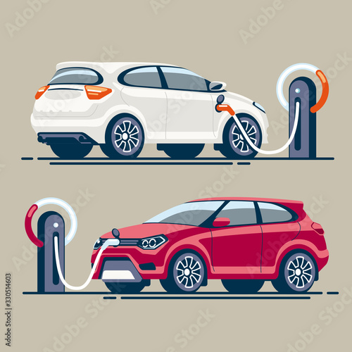 Two electric cars at a gas station are charged with electricity through an electric cable with a connector.