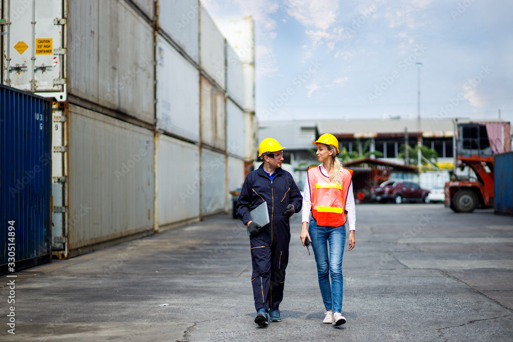Foreman and worker staff wearing a yellow helmet walking in a industrial shipping yard. He's consulting on exporting goods overseas. Container transportation and export with commercial docks. Foreman and worker staff wearing a yellow helmet walking in a industrial shipping yard. He's consulting on exporting goods overseas. Container transportation and export with commercial docks.