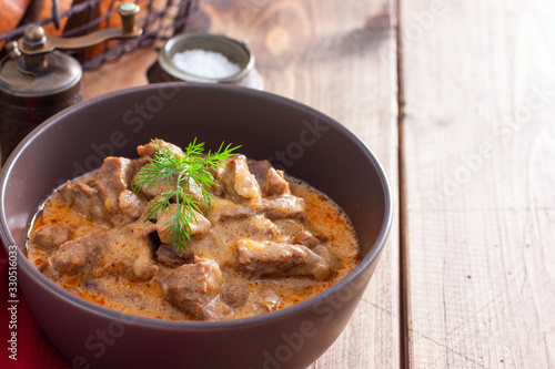 Traditional beef stroganoff in ceramic bowl on a wooden table, horizontal, copy space