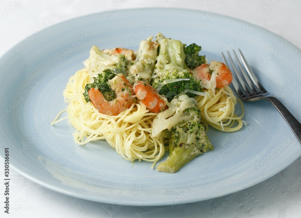 Creamy pasta with broccoli and shrimp on a blue plate with a fork