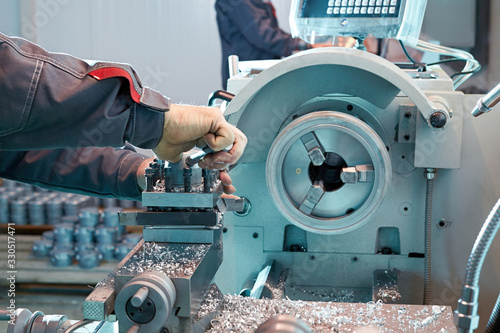 A closeup of a worker sets a workpiece in a lathe