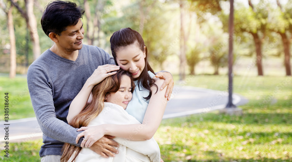 Asian family has Father and mother hugging their daughters, standing happy with a smile in the park. Asian family has Father and mother hugging their daughters, standing happy with a smile in the park.