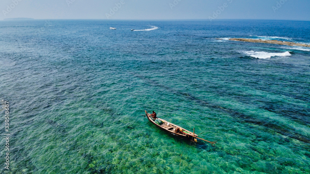 Naklejka premium NGWE SAUNG/MYANMAR - MARCH 14, 2020 : Burmese fishermen bear caught fish in baskets on the beach Ngwe Saung Myanmar