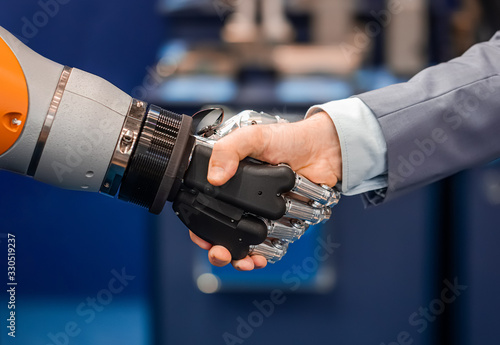 Hand of a businessman shaking hands with a Android robot.