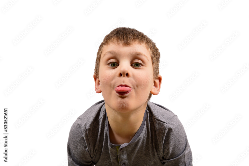 A small cheerful boy shows his tongue to the camera on a white background A small cheerful boy shows his tongue to the camera on a white background