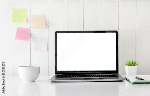Digital technology Laptop muck up blank white screen and flower pot book, note paper,coffe cup on white table ,Home interior or office background