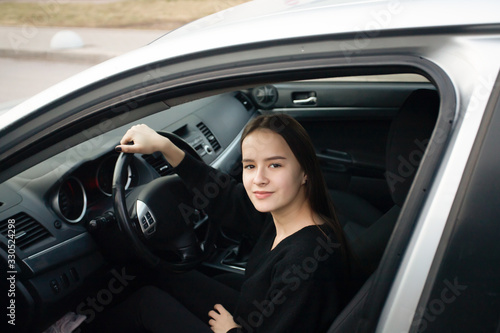 Young woman in a driving school, learning to drive, sitting in a car, smiling