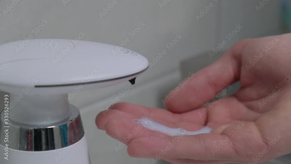 Automatic dispenser of liquid soap in the bathroom close-up. A young guy washes his hands. Automatic dispenser of liquid soap in the bathroom close-up. A young guy washes his hands.