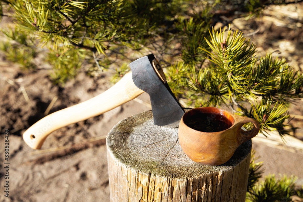 View of camp axe and cup of tea in a forest. Bush craft concept. Stock  Photo