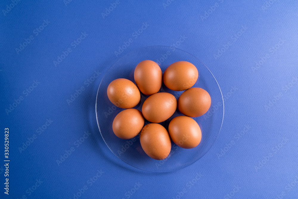 Brown eggs on a glass plate on blue background. Brown eggs on a glass plate on blue background.