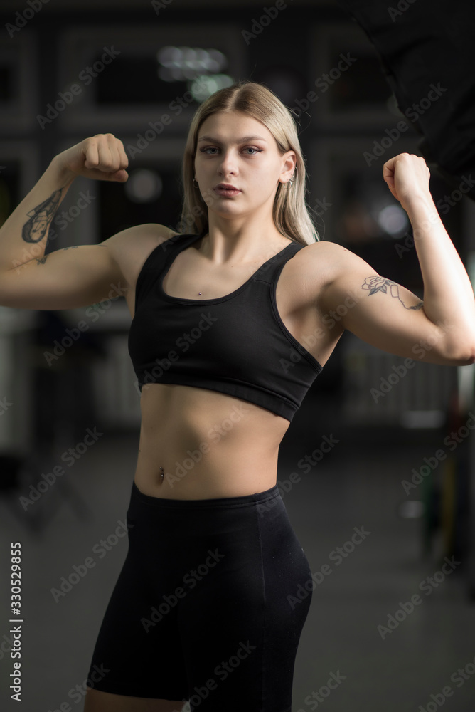 Portrait of a blond-haired girl with in the gym standing in a sports position. Portrait of a blond-haired girl with in the gym standing in a sports position.