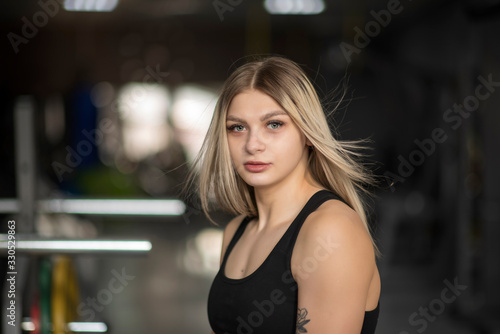 Portrait of a blonde girl with developing hair in a fitness gym.