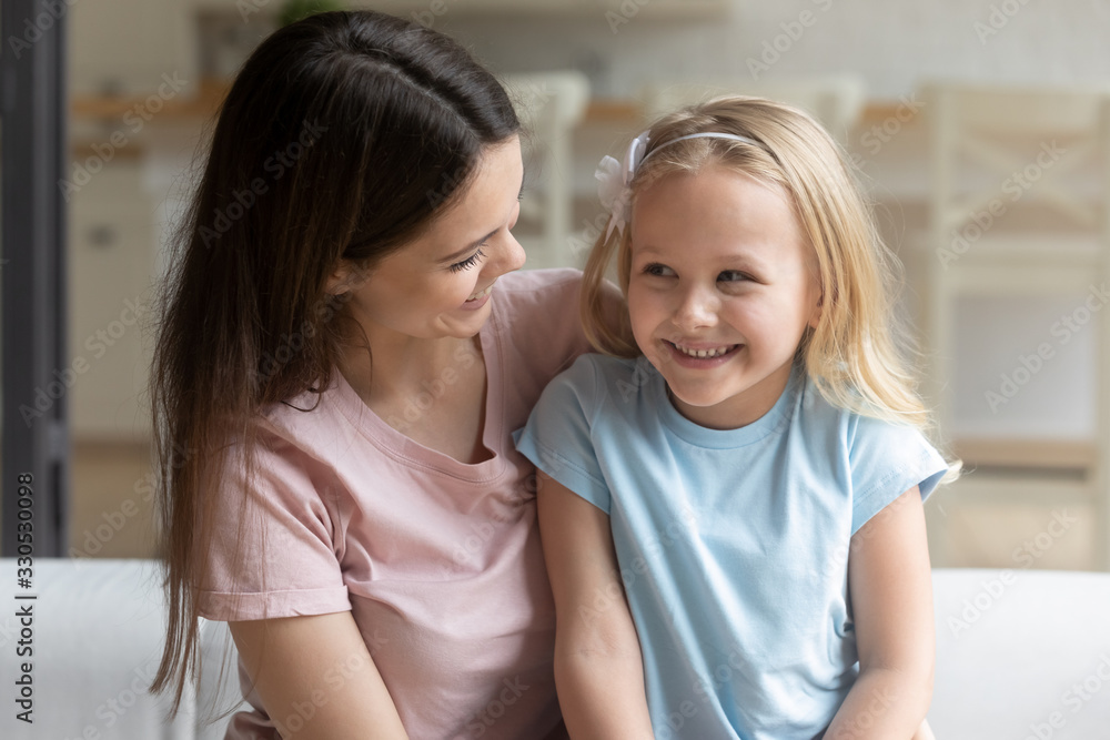 Close up of loving happy young mom sit relax with cute little preschooler daughter having fun at home together, smiling mother and small girl child rest enjoying family weekend or leisure time Close up of loving happy young mom sit relax with cute little preschooler daughter having fun at home together, smiling mother and small girl child rest enjoying family weekend or leisure time