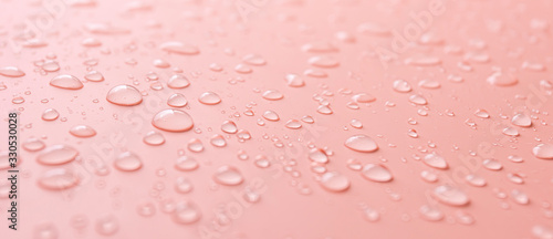 Lots of different rain water drops on a pink background, side view