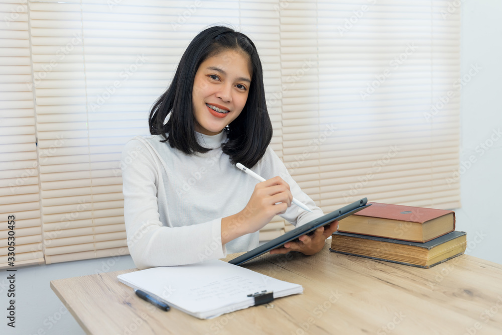 Young cheerful Asian student female university student studying in self study room in the university library to do her assignment and prepare for examination. Young cheerful Asian student female university student studying in self study room in the university library to do her assignment and prepare for examination.