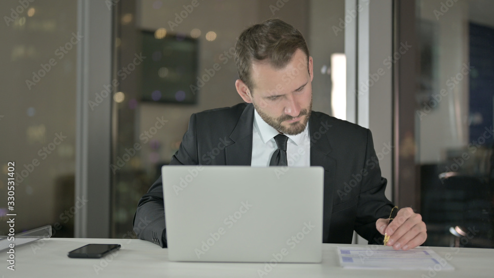 The Young Businessman working on Laptop and Document at Night