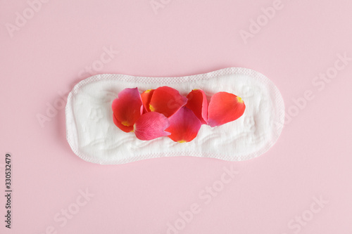 red rose flower petals on scented menstruation pad isolated on pastel pink background, flat layout, top view, intimate hygiene