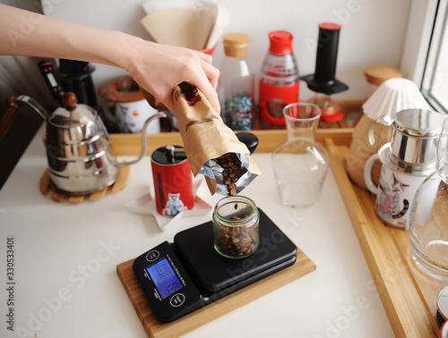 Alternative manual brewing bar. Pouring coffee beans into glass jar on scale. Home barista