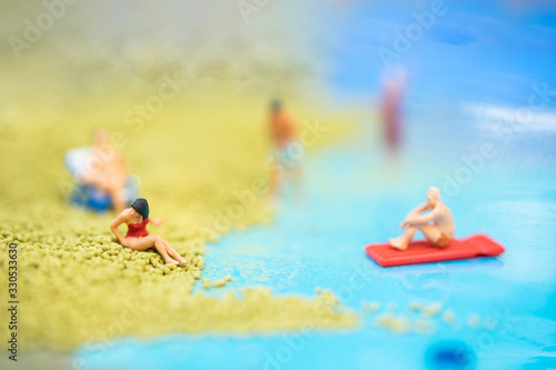 Miniature people, travelers relaxing on the sand box decorating in summer theme using as background travel, exploring the world, budget trip concept. © noppawan09