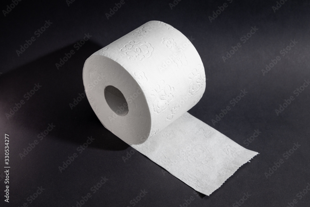Fototapeta Toilet paper on a roll against a black background
