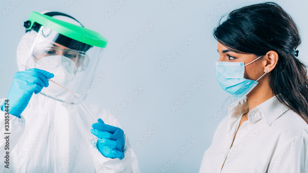 Coronavirus test. Medical worker in protective suite taking a swab for corona virus test, potentially infected young woman Coronavirus test. Medical worker in protective suite taking a swab for corona virus test, potentially infected young woman
