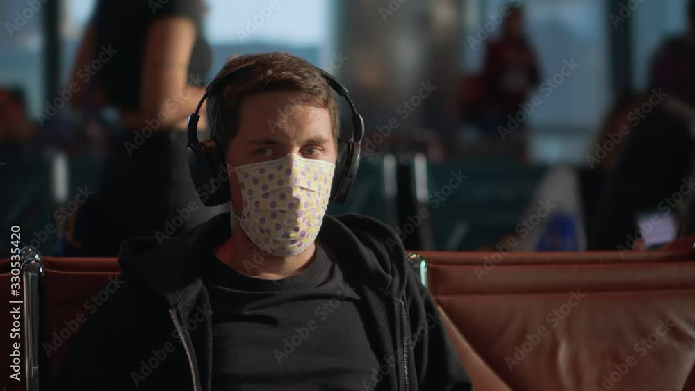 Man in headphones wearing mask to be safe from coronavirus at the airport Man in headphones wearing mask to be safe from coronavirus at the airport