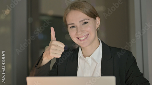 The Close Up of Businesswoman showing Thumbs Up in Office at Night