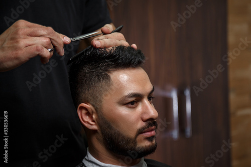 the guy is a dark-haired Asian Indian appearance on a haircut in a barbershop . cinematic image