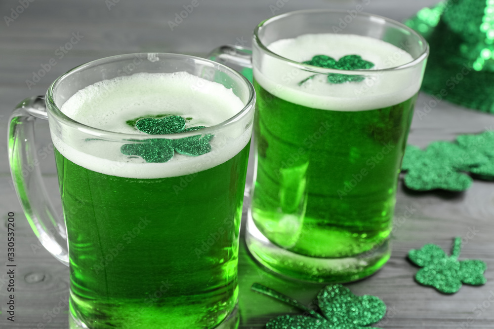 Green beer and clover leaves on grey wooden table, closeup. St. Patrick's Day celebration Green beer and clover leaves on grey wooden table, closeup. St. Patrick's Day celebration