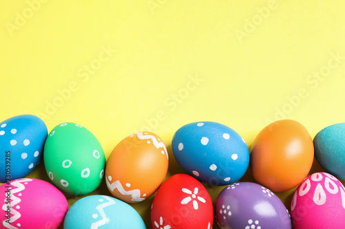 Fototapeta Colorful Easter eggs on yellow background, flat lay. Space for text