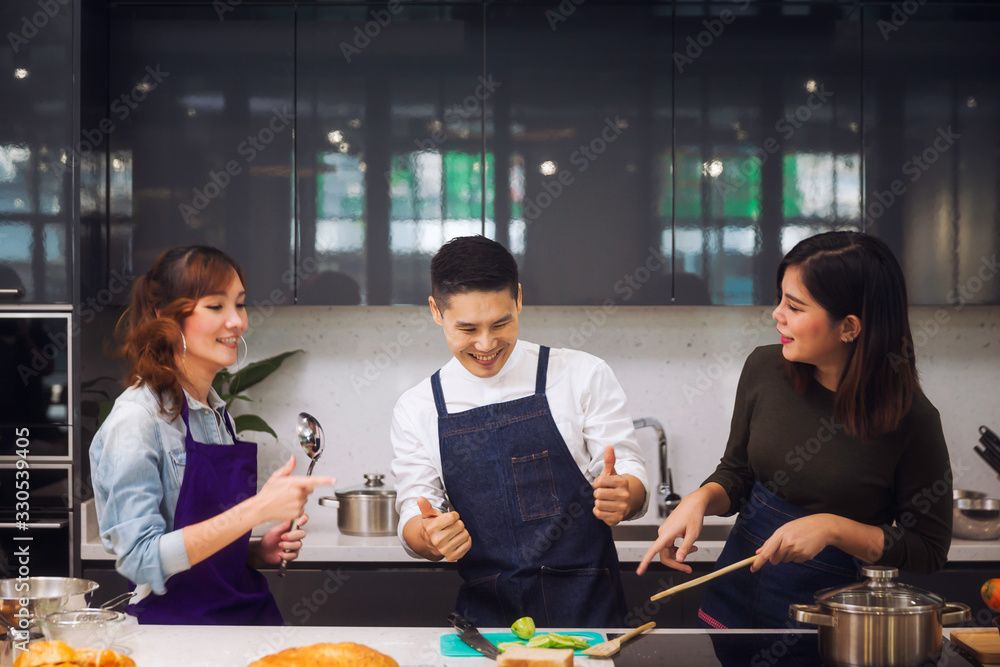 Asian people. Man and woman cooking dinner for guests. Young people are enjoying cooking. Group of friends at home party. Asian people. Man and woman cooking dinner for guests. Young people are enjoying cooking. Group of friends at home party.