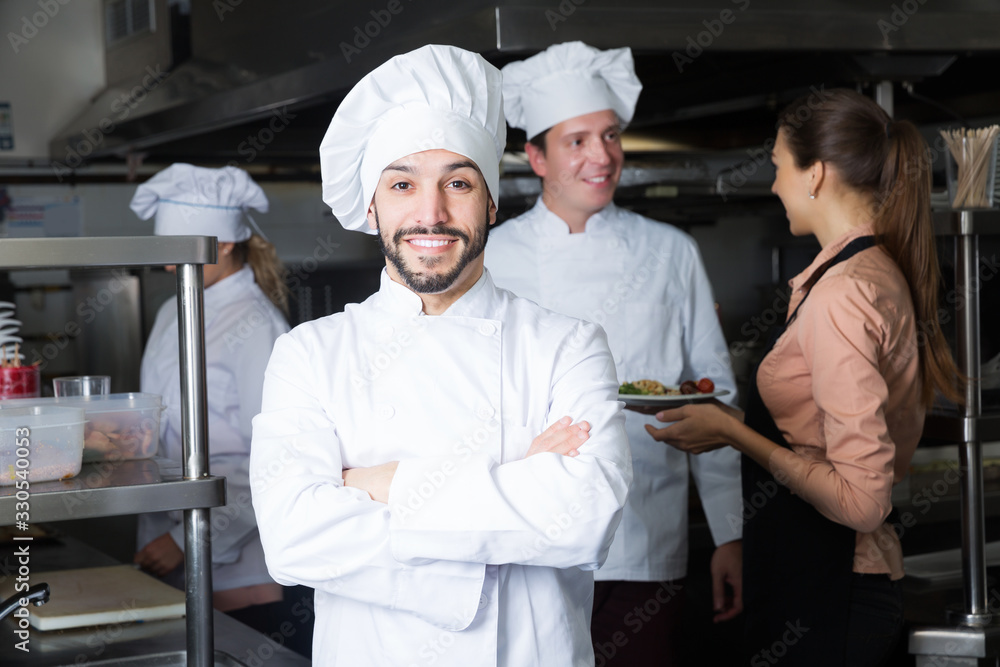 cheerful chef in kitchen with staff