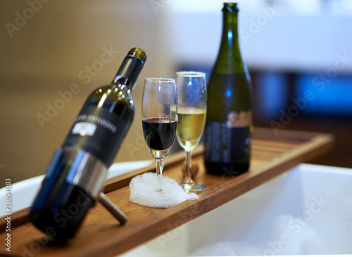 red and white wine in tall glasses on wooden palatte with bubbles on bathtub photo