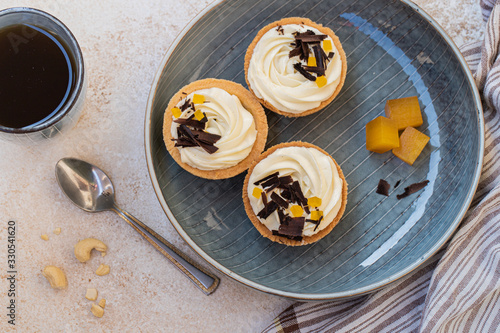 homemade shortbread tartlets or cupcakes with delicate cream and orange jam, decorated with chocolate chips. natural sweets concept. cozy tea party