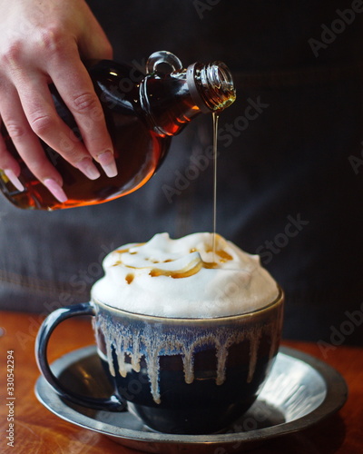 Latte hot drink topped with maple syrup at a local cafe in Ontario, Canada. Spring themed mug of tea with maple syrup from a local sugar shack.