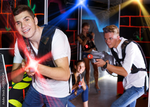 Group of young smiling friends with laser pistols playing laser