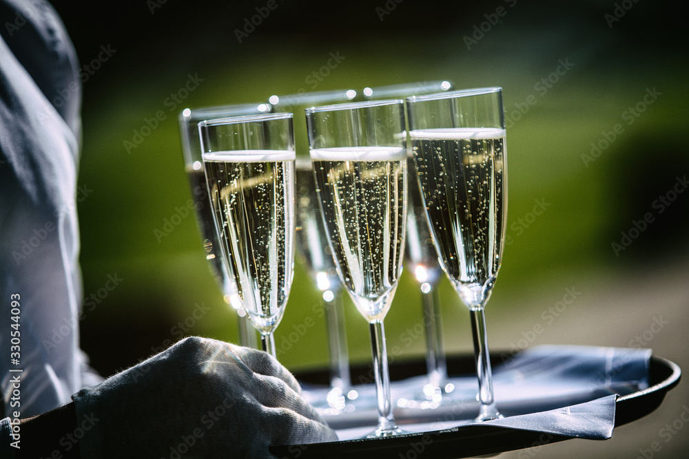 a waiter carries glasses of champagne