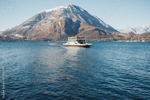 Passenger ship crossing Lago di Como, Italy. Sunny snowy mountain landscape background
