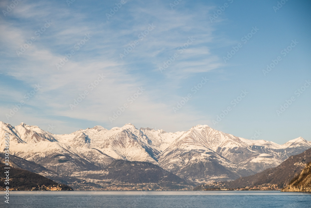 Panoramic of  snowy mountain reflected in Lago di Como in Italy, clear and sunny sky. Rule of thirds