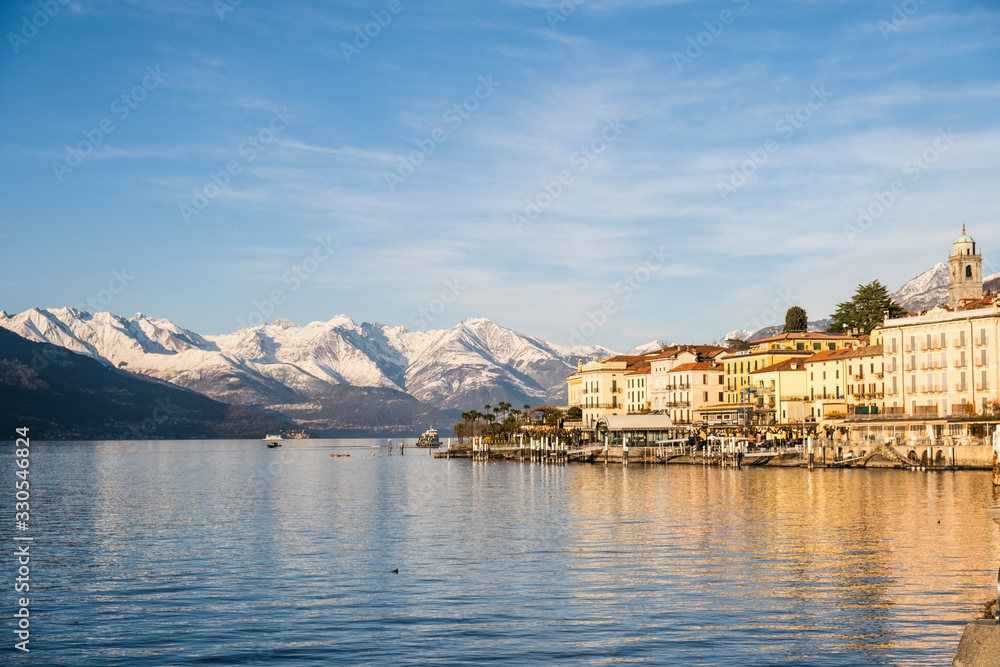 Spectacular landscape of Bellagio, an Italian town with snowy mountains in the background, reflected on the shores of Lago Di Como