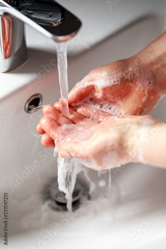 woman washing hands with antibacterial soap under running water