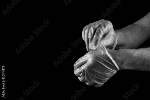 Man taking off medical rubber gloves , isolated on black background copy space photo