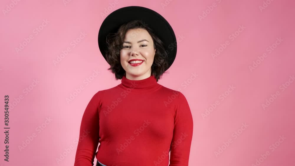 Beautiful young woman in a hat look at the camera and smiling. Satisfied customer. Portrait of happy female millenal in studio. Close up of fashion model. Beautiful young woman in a hat look at the camera and smiling. Satisfied customer. Portrait of happy female millenal in studio. Close up of fashion model.