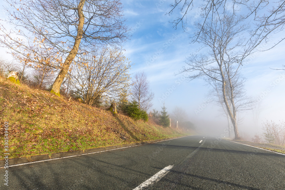Fototapeta premium Bergstrasse im Sonnenaufgang und Nebel